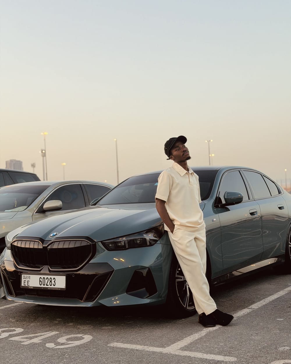 Chancio adossé à une berline au coucher du soleil, dernier jour de tournage à Dubaï