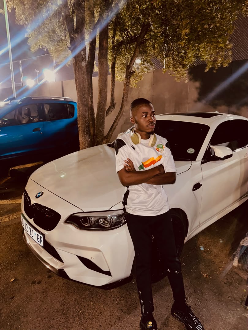 Chancio adossé à une BMW blanche de nuit, à Pretoria